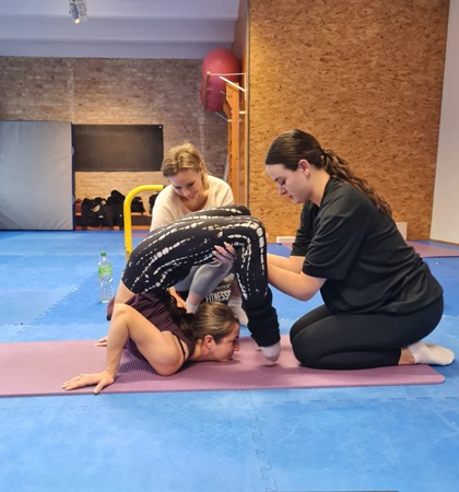 Teilnehmer eines Teacher Trainings lernen richtiges Sichern bei Kontorsionstricks unter Anleitung der Ausbilderin.