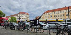 Frau macht Spagat im Freien auf Fahrradständern vor Wohnhäusern