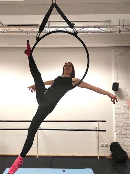 Eine Frau in schwarzer Sportkleidung macht einen Trick im Aerial Hoop in einem Akrobatikstudio