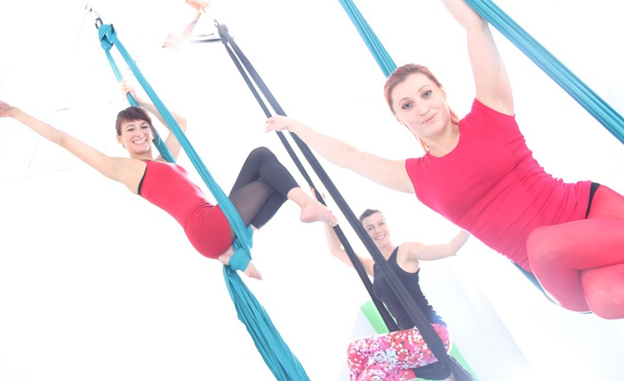 3 Frauen in bunter Sportkleidung machen Akrobatik in Aerial Silks