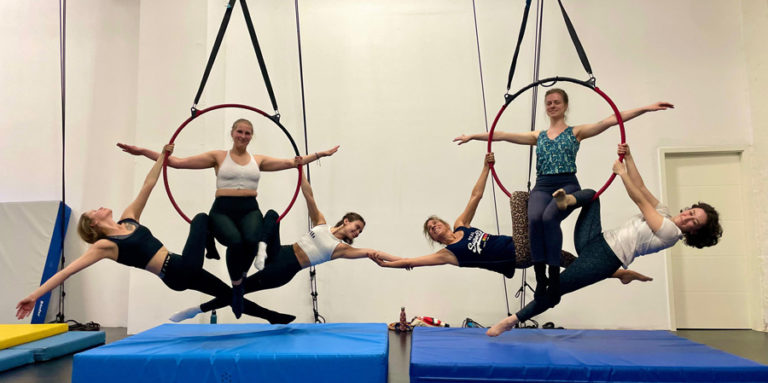 Sechs Frauen zeigen Gruppen-Tricks am Aerial Hoop in 3er-Gruppen